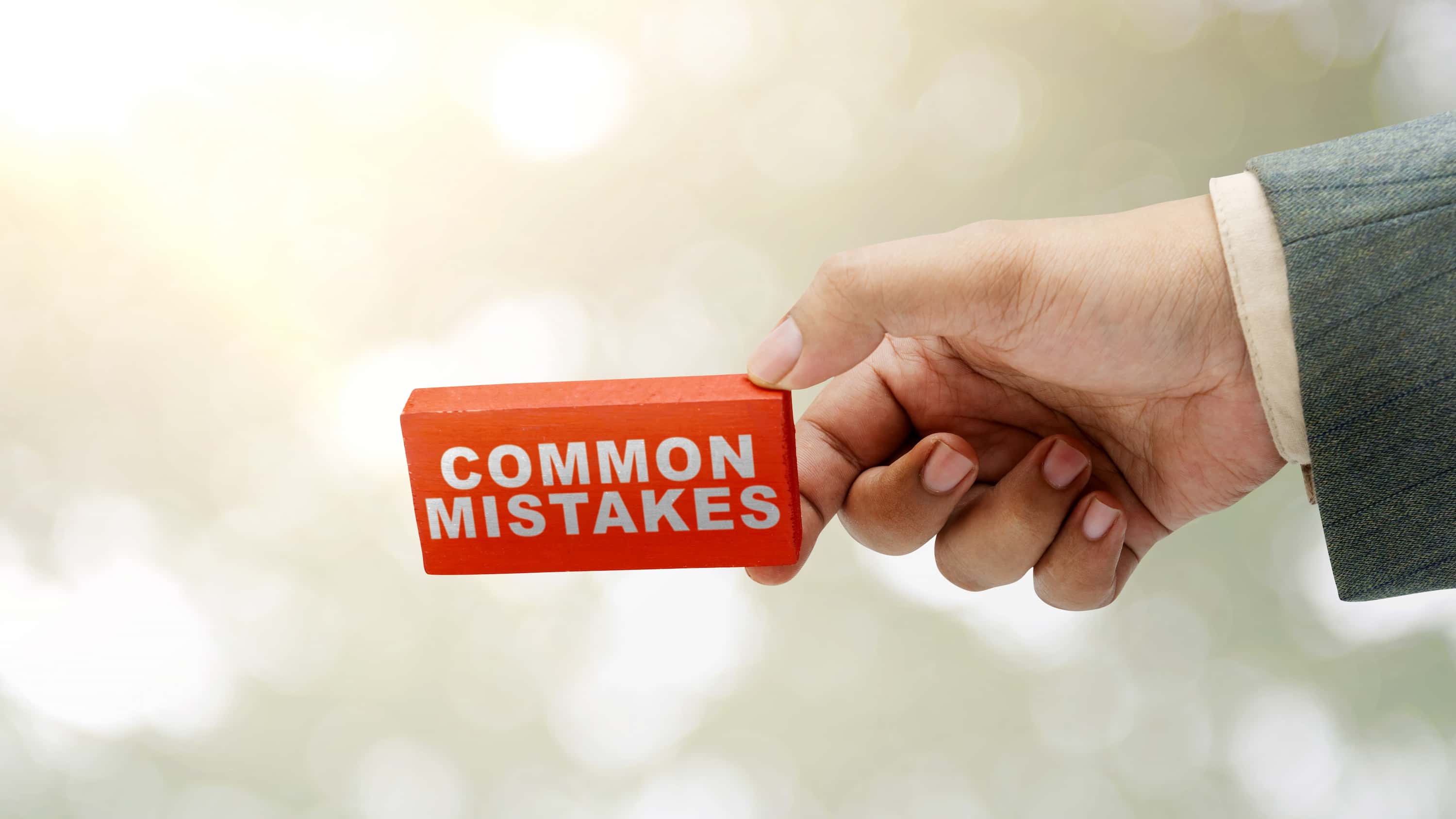 Section image - image of hand holding a sign that says common mistakes