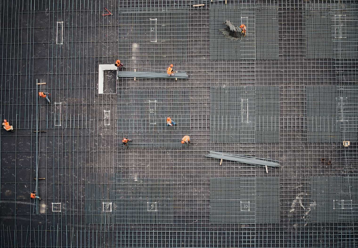 Section image - credit saad-salim-PqRvLsjD_TU-unsplash - aerial shot of construction workers framing a building
