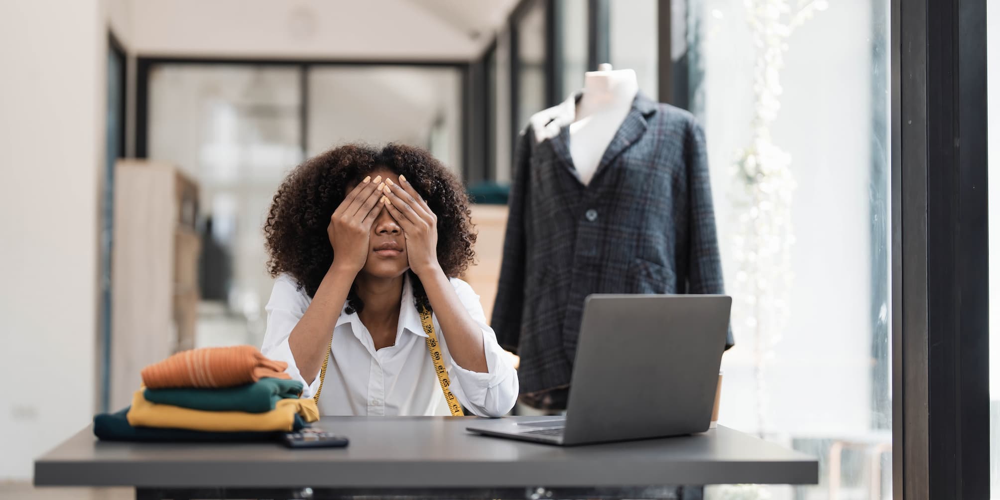 Section image - woman looking stressed in front of a desk with retail clothes and a tape measure around her neck